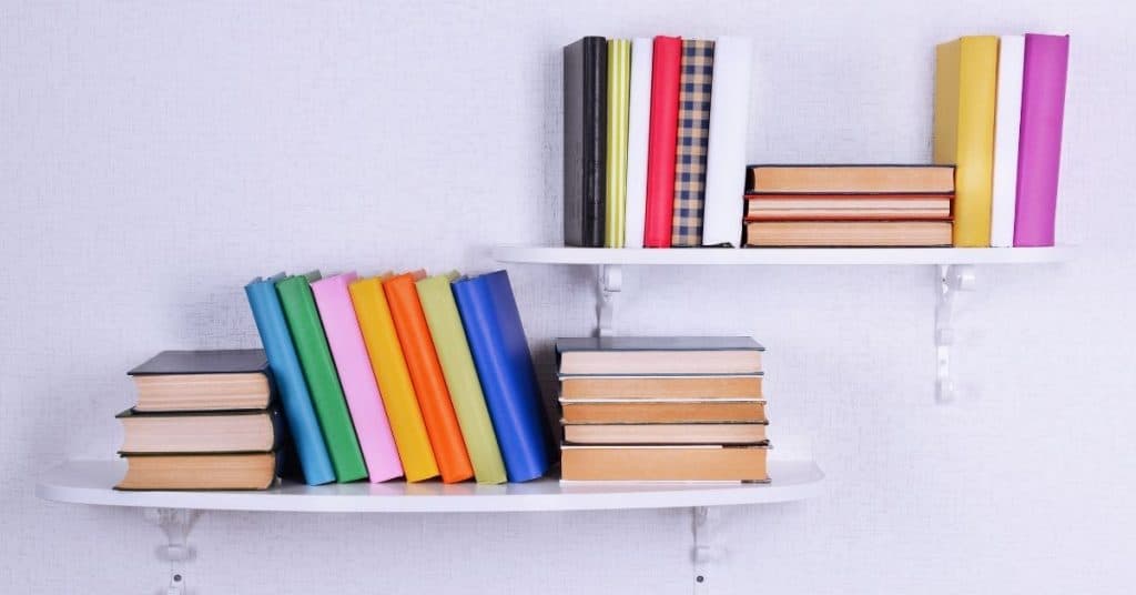 wall with two floating shelves with different colored books on them. Simple way to enhance a blank wall by adding floating shelves or shelving units